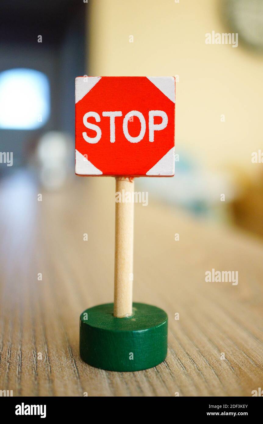 A small red stop sign on a wooden table under the lights with a blurry background Stock Photo
