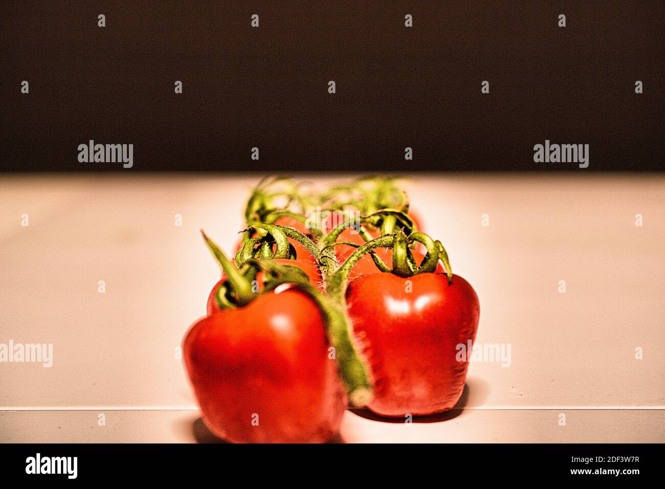 Cherry tomatoes on white table and black background Stock Photo
