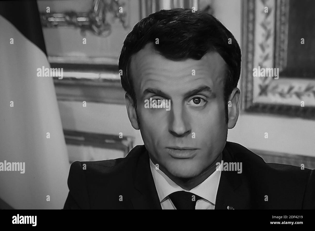 Emmanuel Macron is seen on a television screen as he speaks during a televised address to the nation on the outbreak of COVID-19, caused by the novel coronavirus in Paris, France on March 16, 2020. President Macron has said France is in a state of war against the coronavirus in a televised address, he forbade people from leaving home, except for essential reasons.The French president addresses the nation, with many expecting him to unveil more strict home confinement rules in a bid to prevent the virus from spreading. France has closed down all schools, theatres, cinemas and a range of shops, Stock Photo