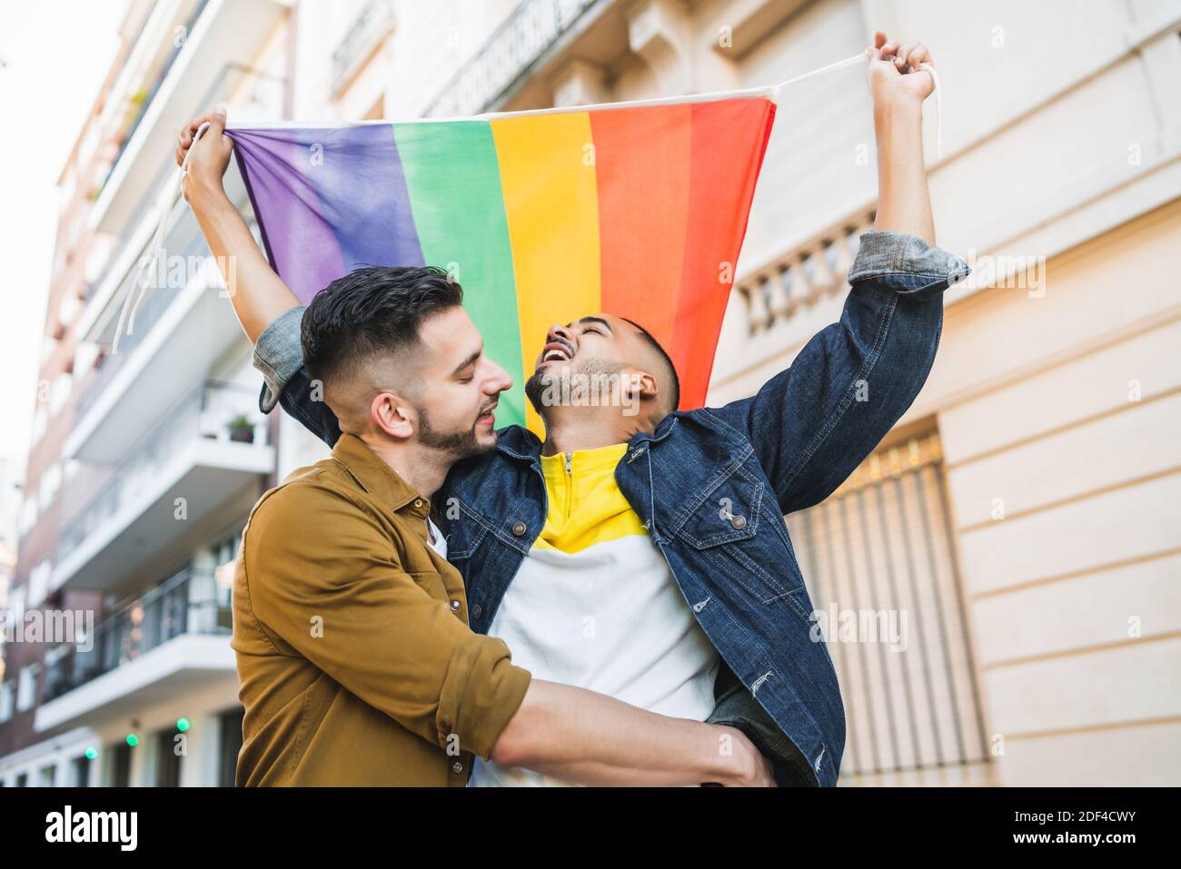 Gay couple embracing and showing their love with rainbow flag Stock ...