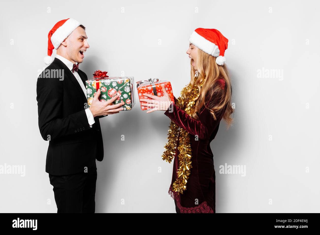 A happy couple of lovers in Santa Claus hats giving each other ...