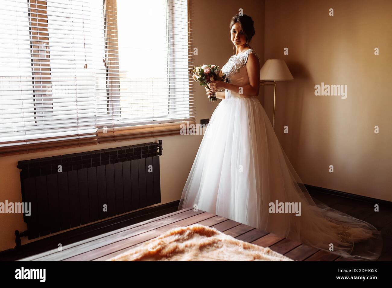 bride poses by the window in a hotel room Stock Photo - Alamy