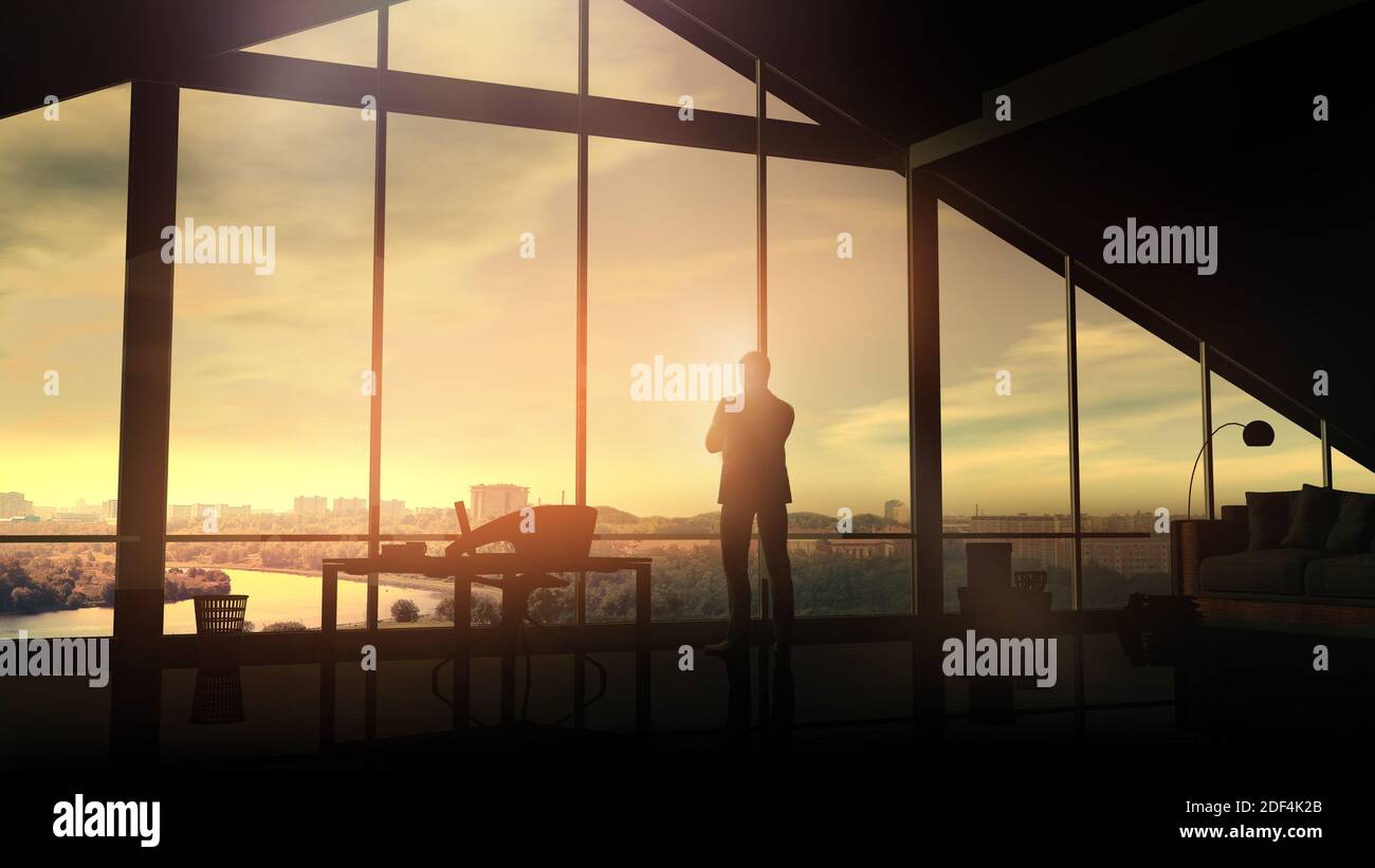 A businessman in his office looks at the cityscape at sunrise. Stock Photo