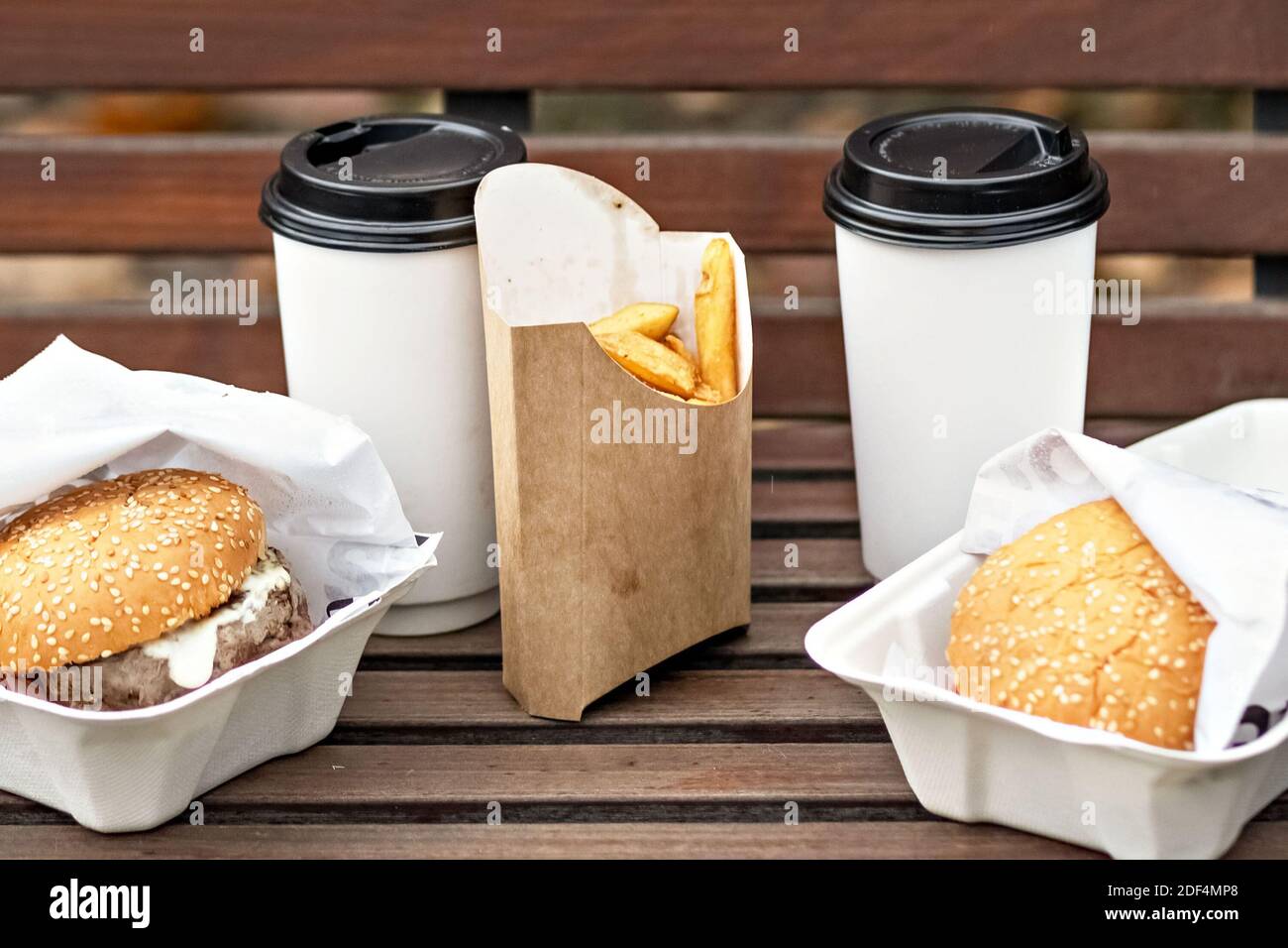 https://c8.alamy.com/comp/2DF4MP8/fast-food-paper-cups-with-coffee-hamburger-boxes-and-fries-on-a-park-benchtakeaway-food-concept-2DF4MP8.jpg