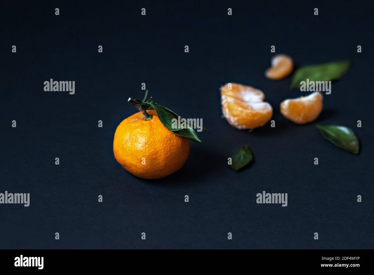 Fresh Mandarin fruit with green leaves isolated on a black background Stock Photo
