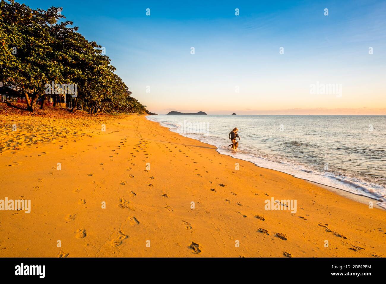 Cairns, Queensland / Australia - June 14 2018: A lady and dog runing along Trinity Beach in the morning Stock Photo