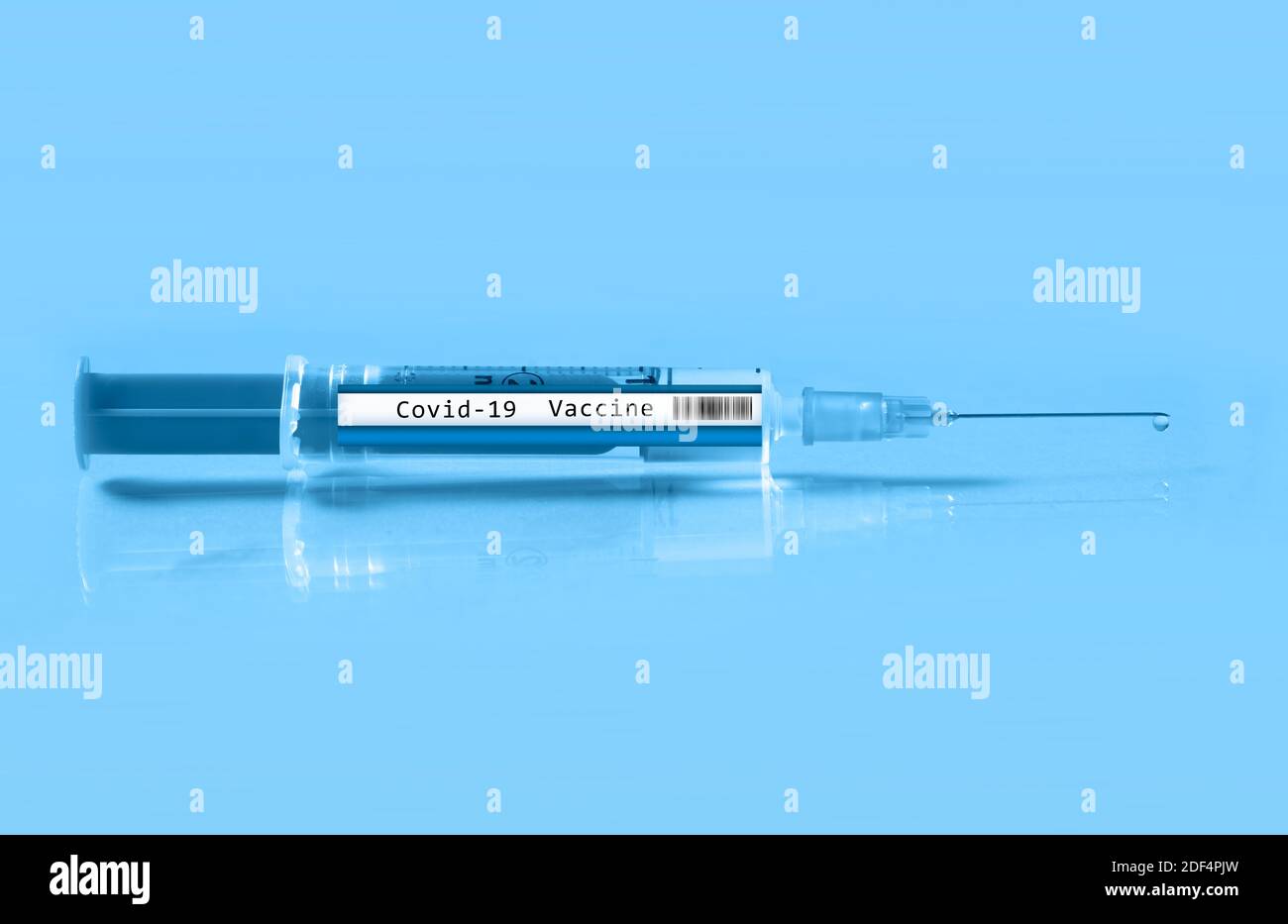 Close up of a syringe labeled Covid 19 vaccine on a light blue ...