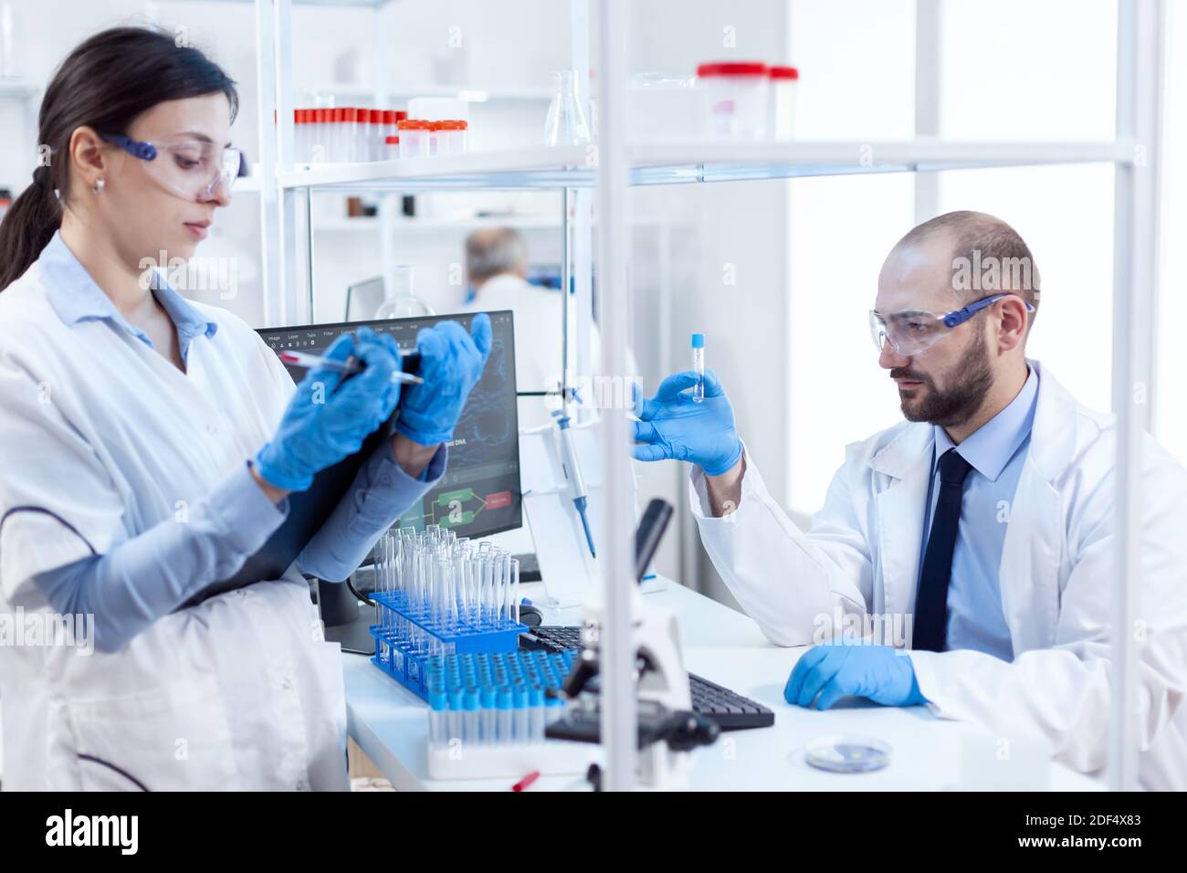 Group of scientist conducting and engineering genetic material analysis. Team of chemical chemists working together in sterile microbiology lab doing research. Stock Photo
