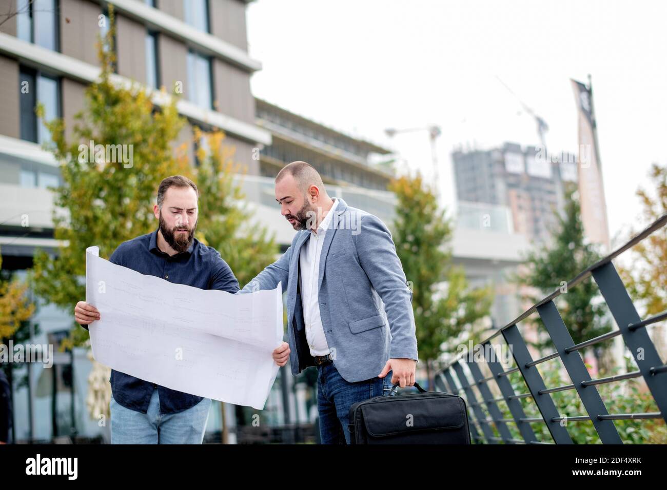 Two young engineers checking the architectural plan outdoors Stock Photo