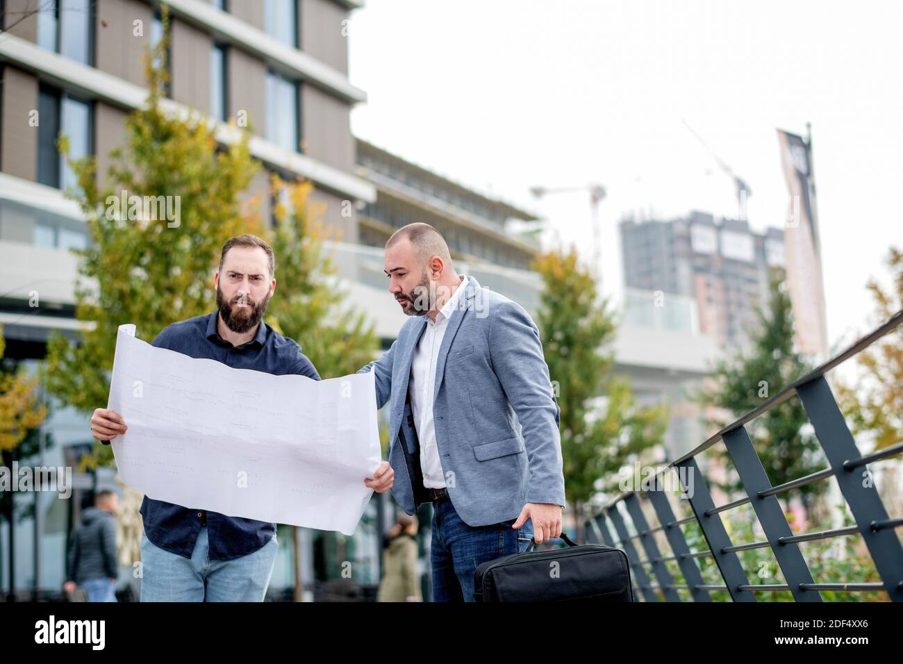 Two young engineers checking the architectural plan outdoors Stock Photo