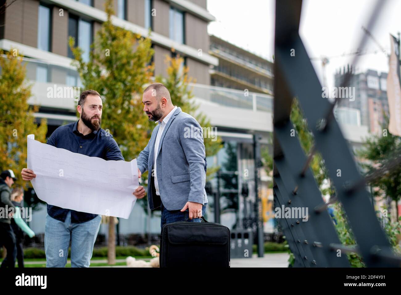 Two young engineers checking the architectural plan outdoors Stock Photo