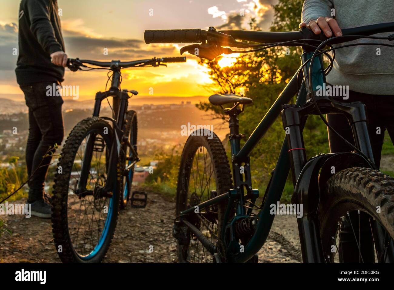 A couple of mountain bikes at sunset on the background of the city. Traveling on mountain bike in nature. Cycling holiday. Stock Photo