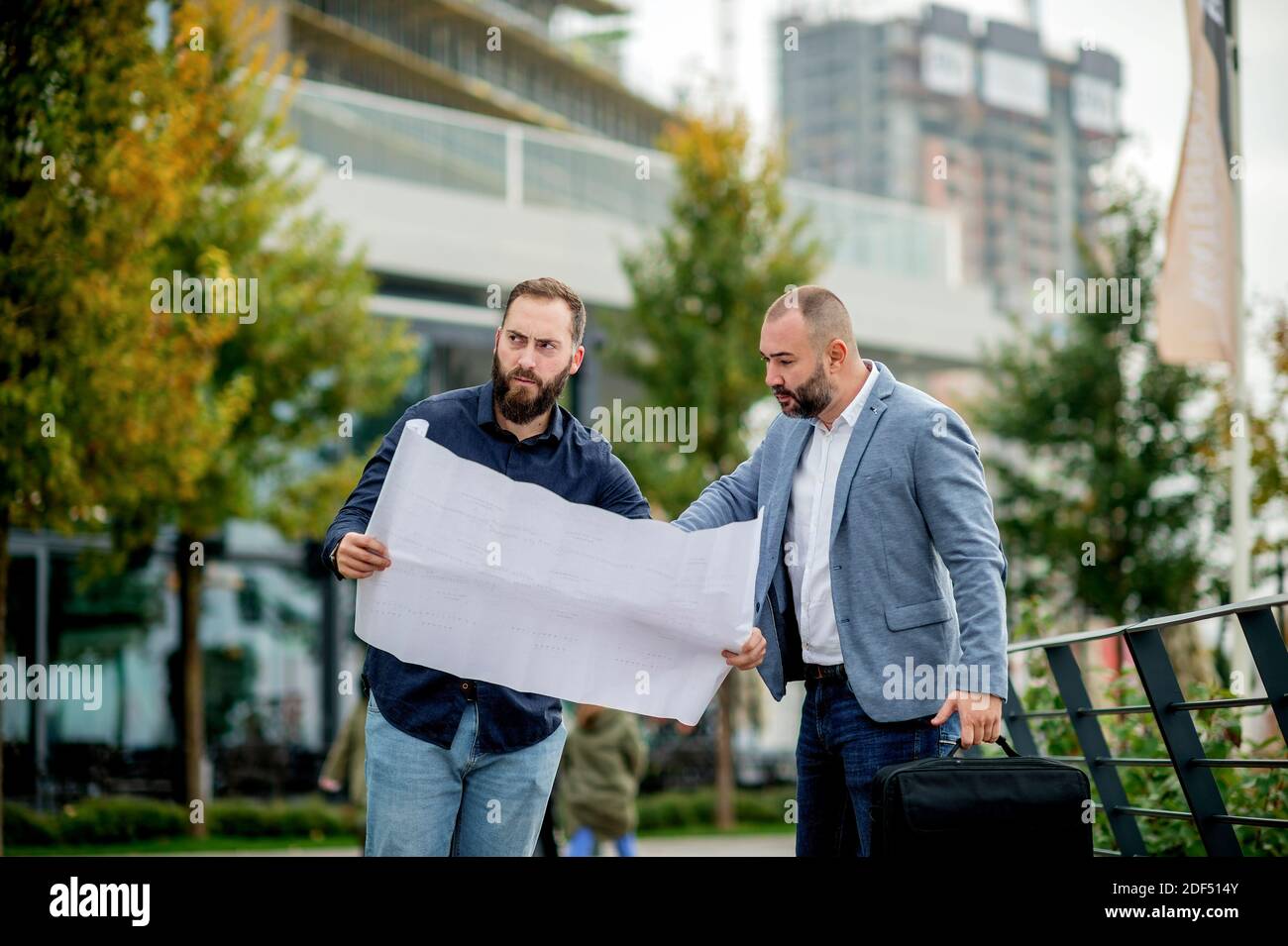 Two young engineers checking the architectural plan outdoors Stock Photo