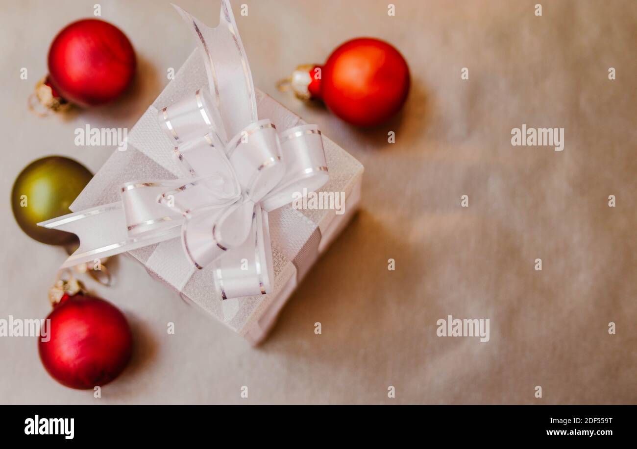 Flat lay composition of small gift box with defocused orange and green Christmas balls around it. Stock Photo