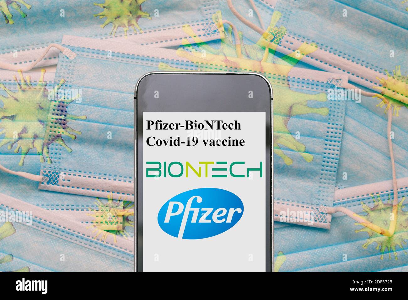 Pfizer biontech covid 19 vaccine. Reino unido vacina. UK approved pfizer vaccine. News on a smartphone. Disposable masks with coronavirus bacteria: NE Stock Photo