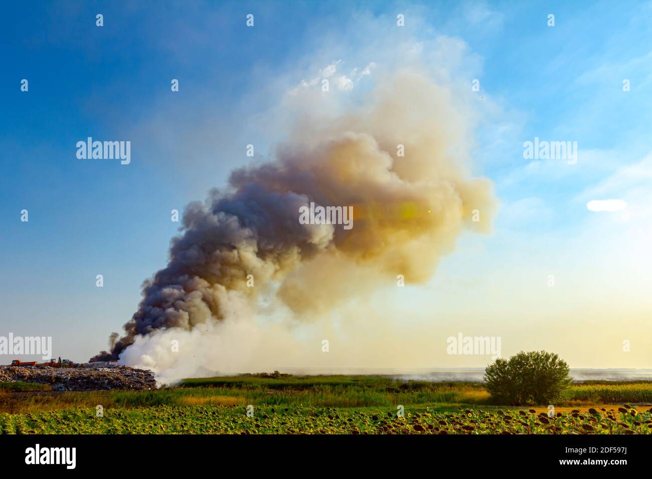 Burning garbage dump pollutes the environment; wind raises toxic smoke