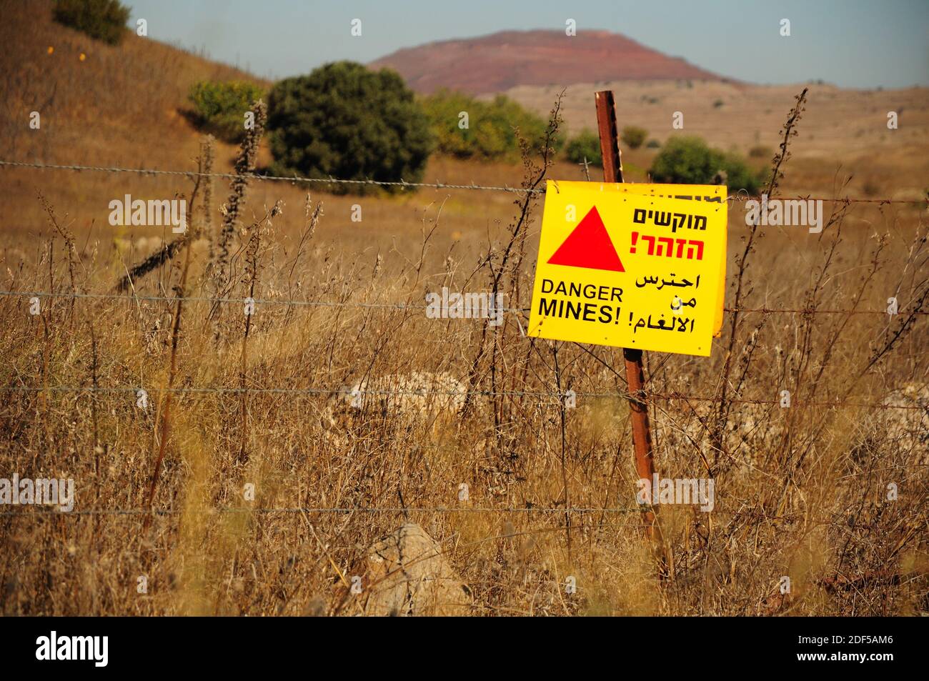Barbed wire fence and signboard warning about minefield at the Golan Heights. Northern Israel. Stock Photo
