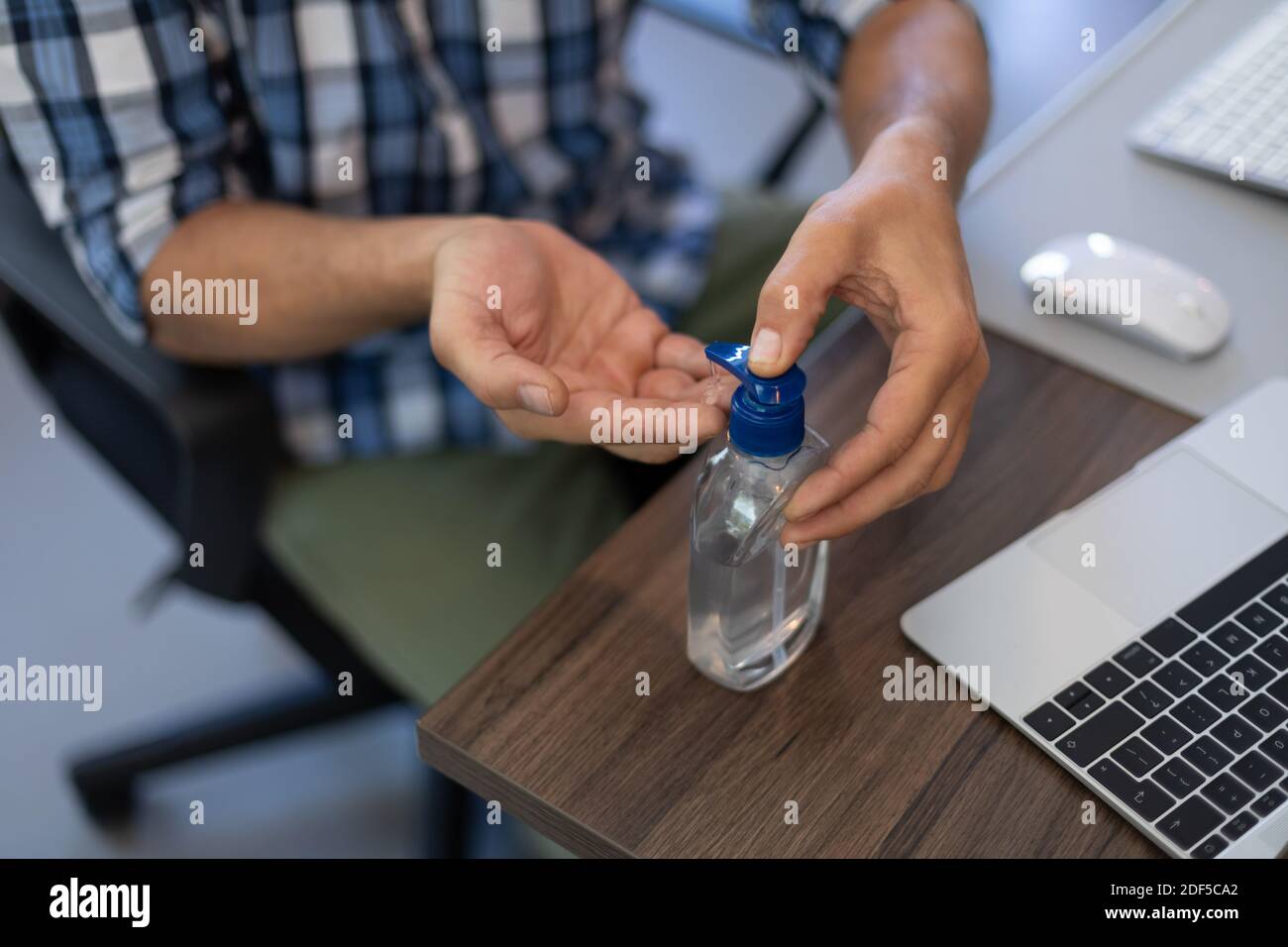 Caucasian man disinfecting his hands in an office Stock Photo