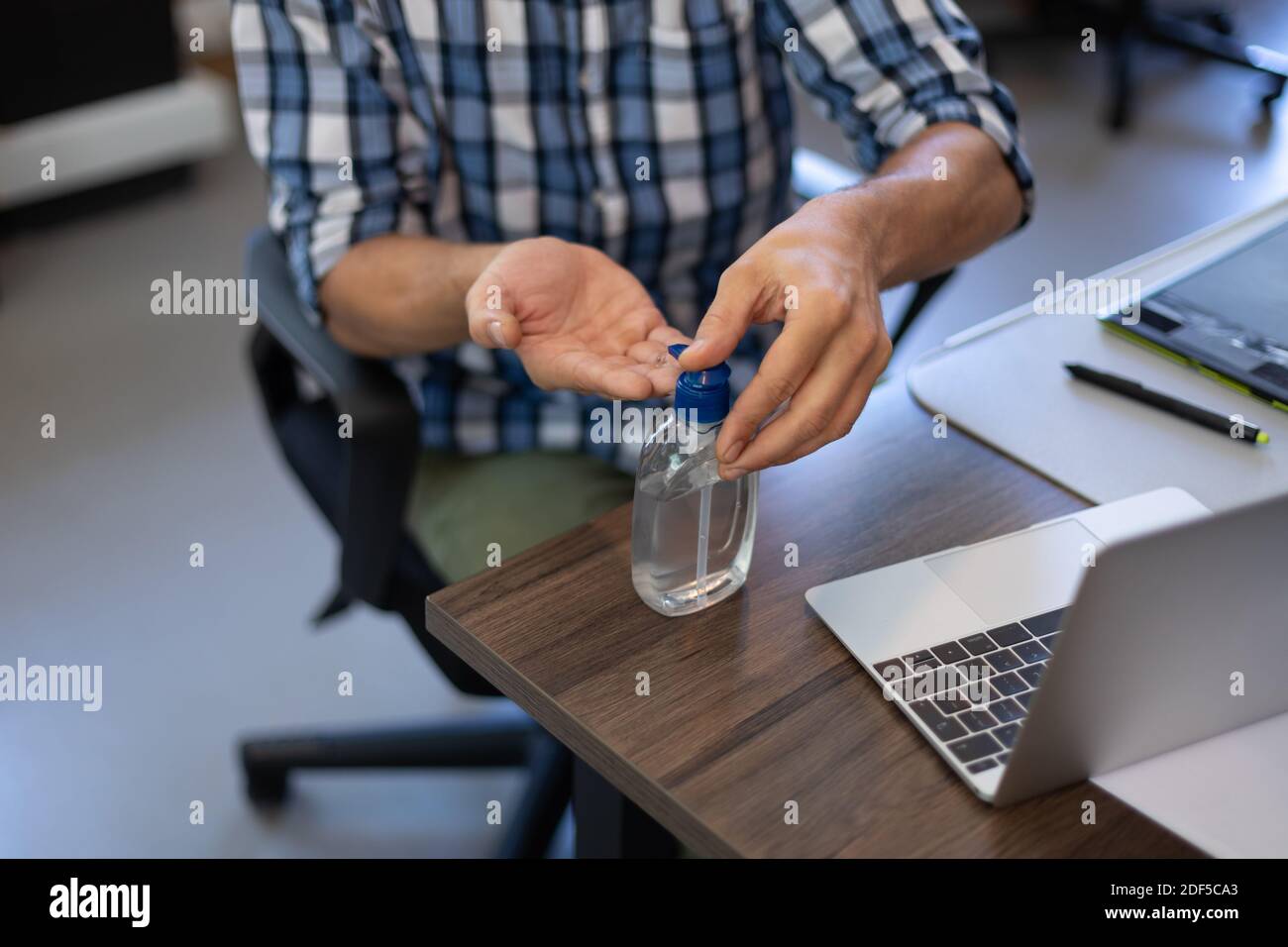 Caucasian man disinfecting his hands in an office Stock Photo