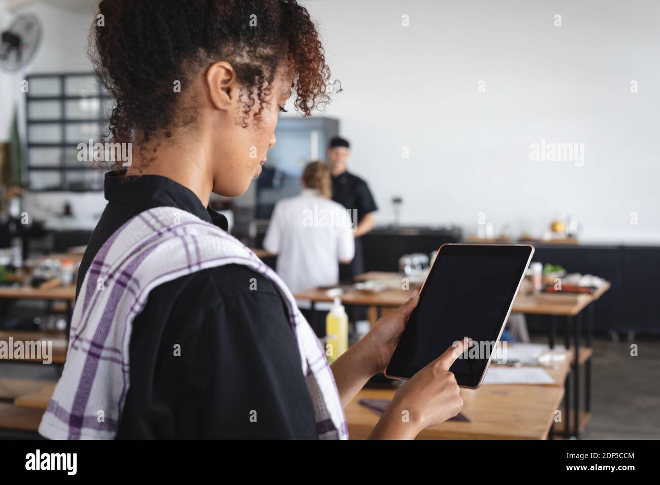 Female african american chef using digital tablet in restaurant kitchen Stock Photo