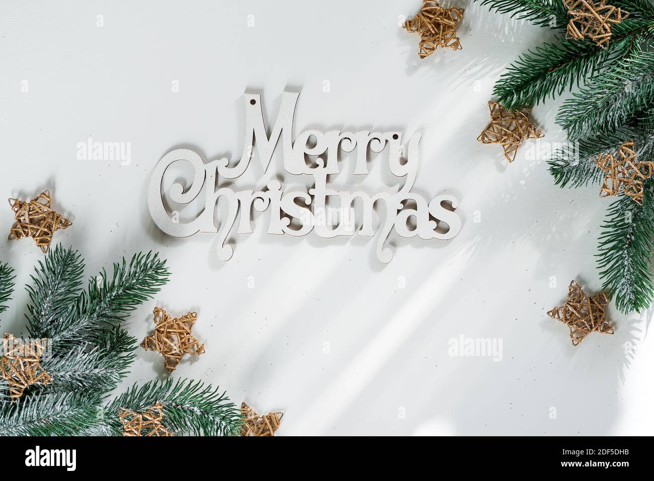 Fir tree branch with gold wooden stars and letters Merry Christmas on ...