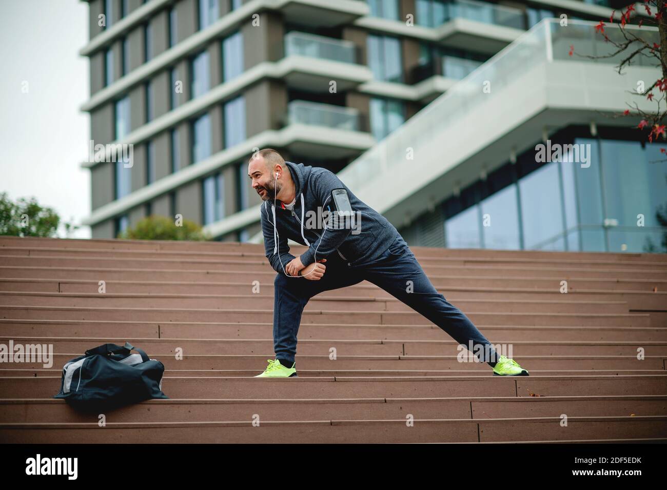 A young man with beard stretching before a run. Stock Photo