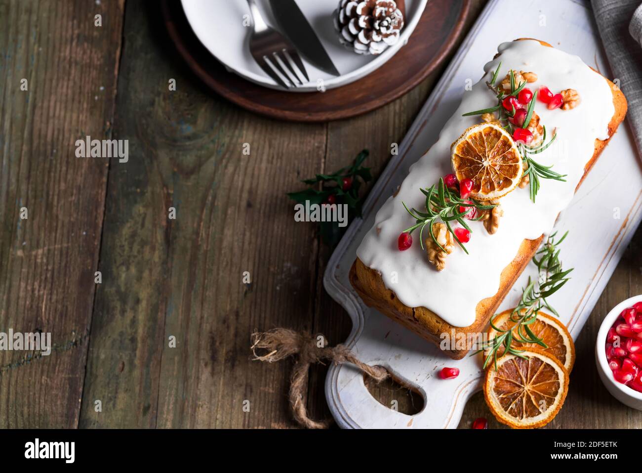 Fruit cake dusted with icing, nuts and dry orange on old wooden background. Christmas and Winter Holidays homemade cake Stock Photo