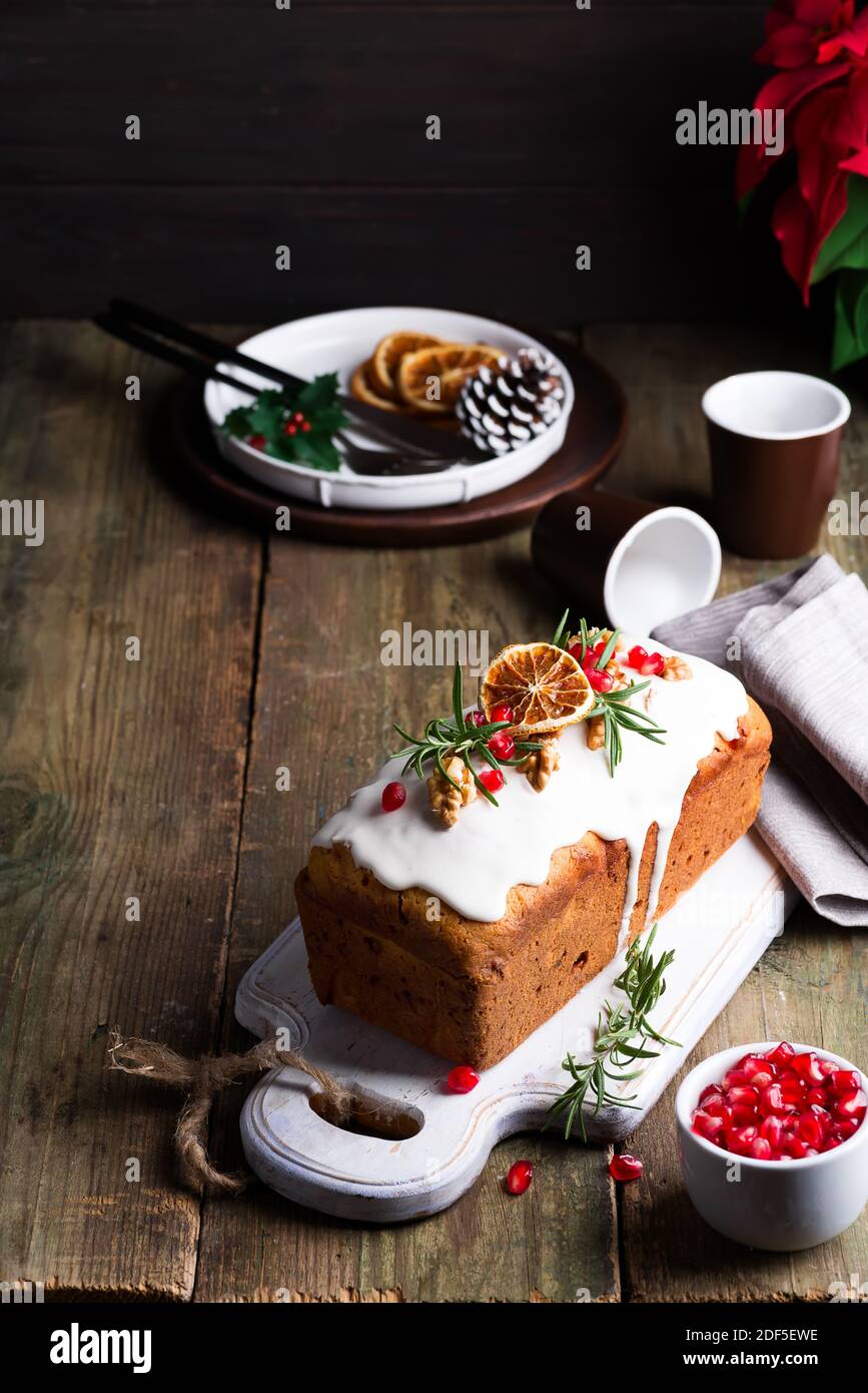 Fruit cake dusted with icing, nuts and dry orange on old wooden background. Christmas and Winter Holidays homemade cake Stock Photo