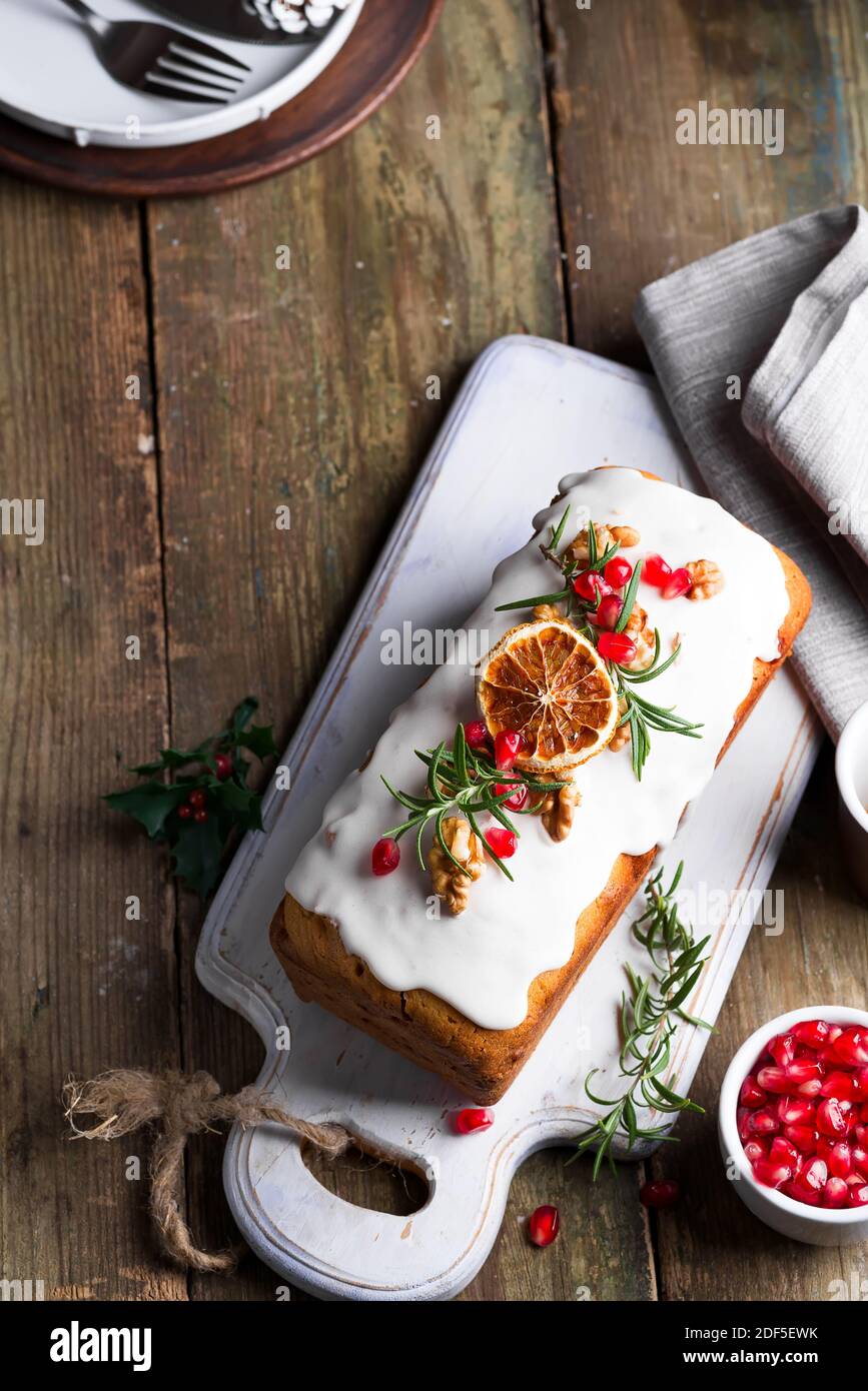 Fruit cake dusted with icing, nuts and dry orange on old wooden background. Christmas and Winter Holidays homemade cake Stock Photo