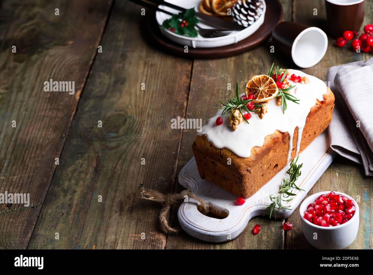 Fruit cake dusted with icing, nuts and dry orange on old wooden background. Christmas and Winter Holidays homemade cake Stock Photo
