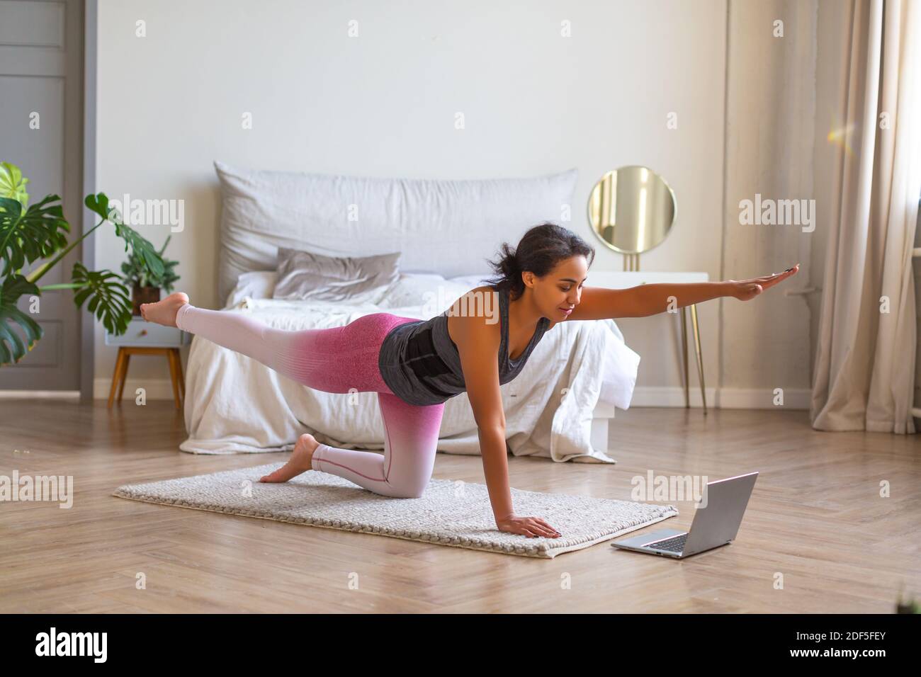 Smiling African American woman during online workout. She follows directions from a trainer on the Internet. Stock Photo