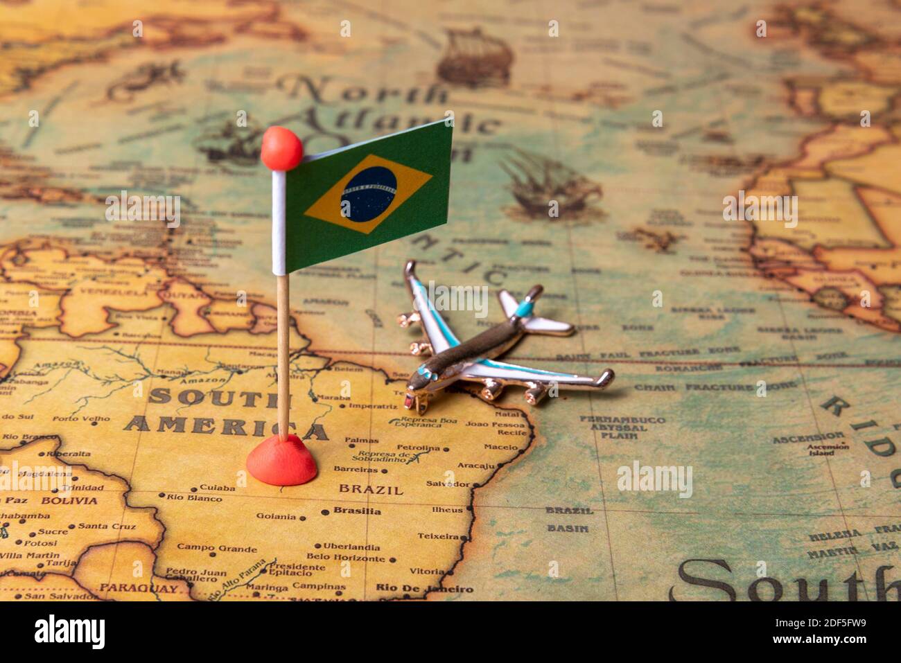 The flag of Brazil and the plane on the world map. The concept of travel and tourism. Stock Photo