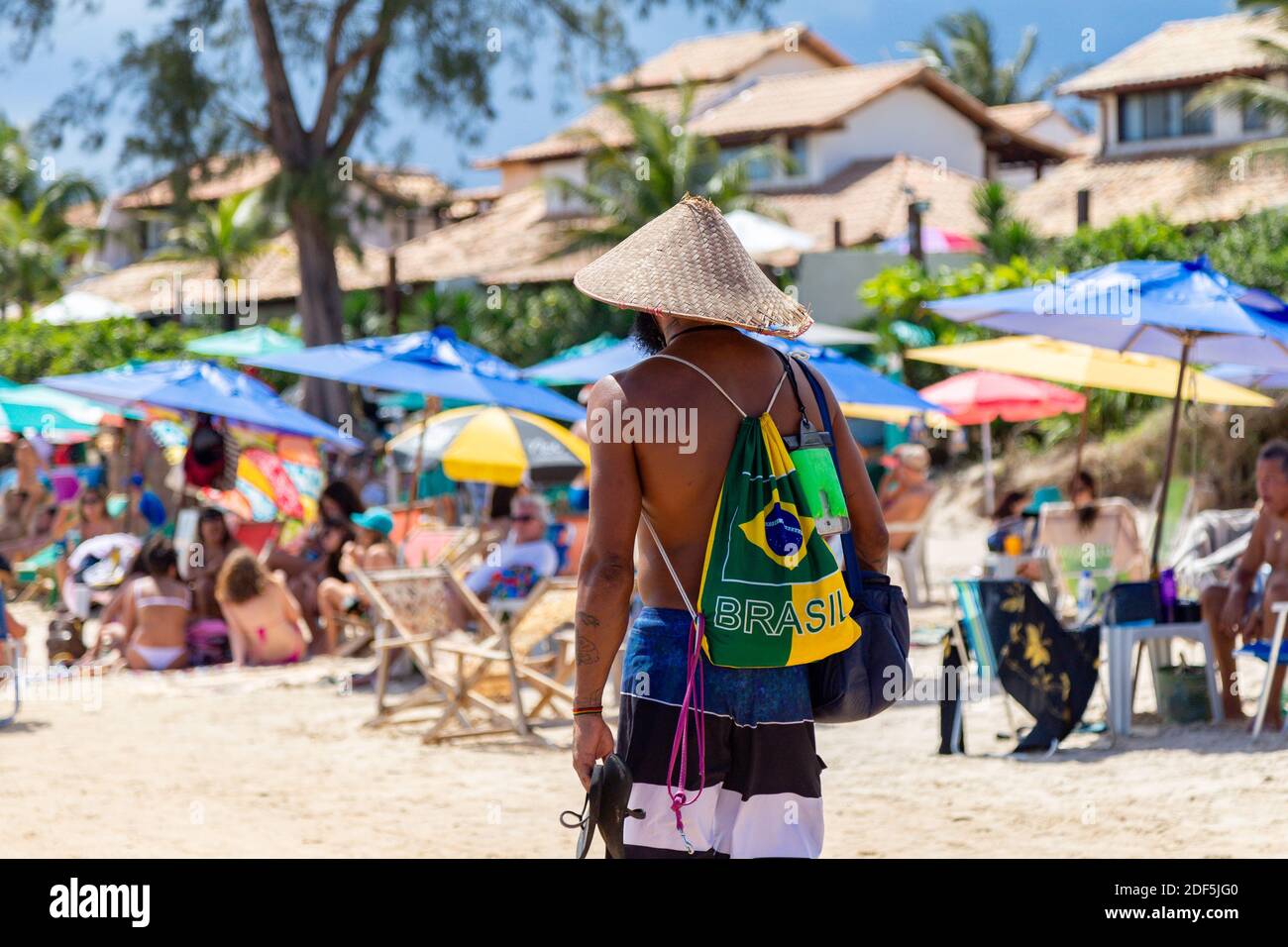 Buzios, Rio de Janeiro, Brazil – December 22, 2019: Brazilian man wearing a traditional backpack with the colors of Brazil. Stock Photo
