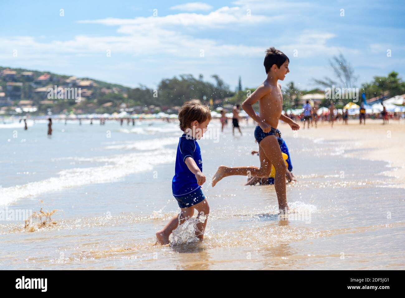 Buzios, Rio de Janeiro, Brazil - December 22, 2019: Boys have fun in Geriba beach. Two children running funny through the water of sea. Stock Photo