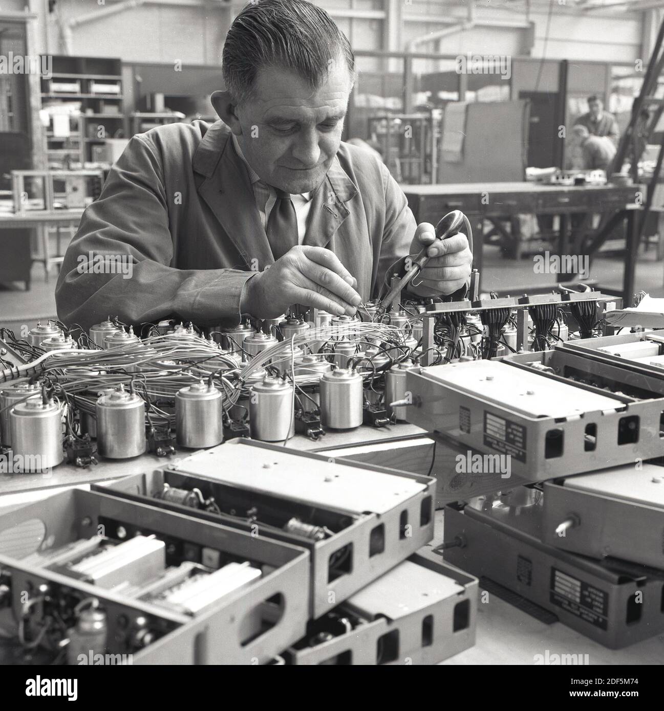 1950s, historical, a skilled aviation technican working on electrical aircraft components using a soldering tool to merge two wires together. Stock Photo