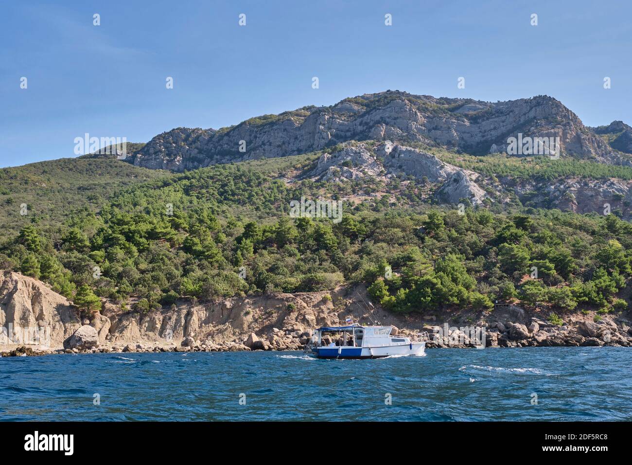 Seascape. The boat sails alongside the rocky coast in the direction of Cape Aya. Balaklava environs, Sevastopol, Crimean peninsula, Russia. Stock Photo