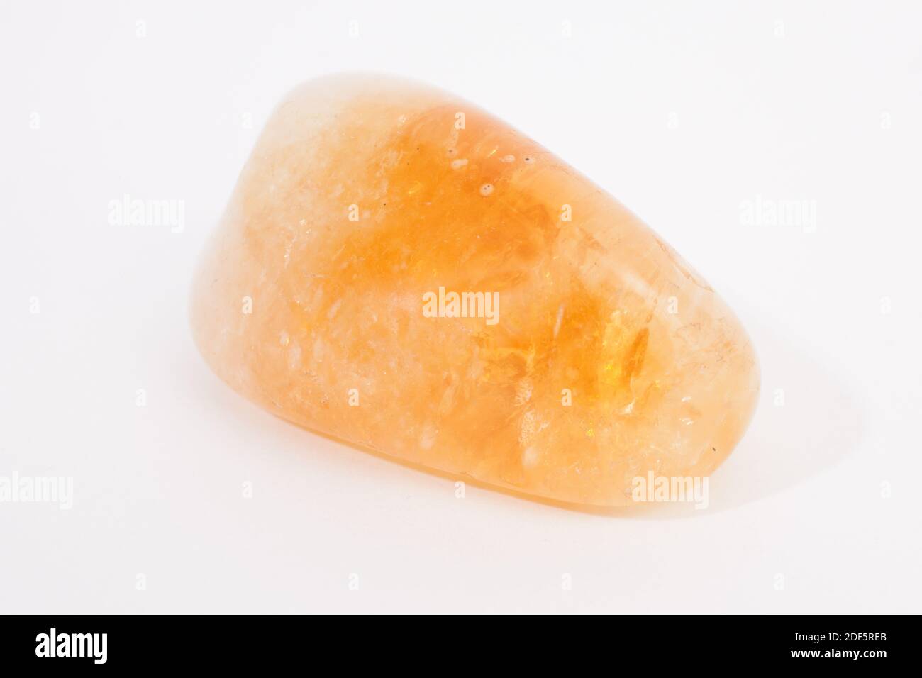 An orange calcite gemstone, shot against a white studio background Stock Photo