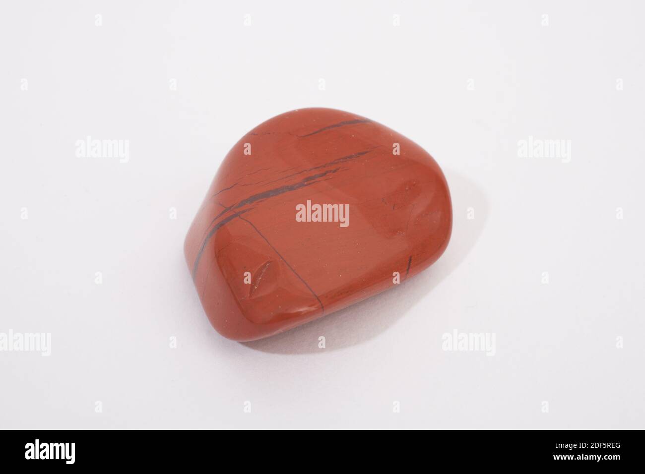 A polished red jasper gemstone shot against a white studio background Stock Photo