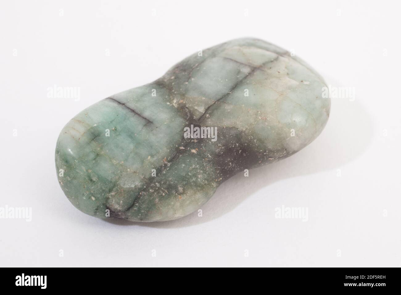 A pale green and grey gemstone shot against a white studio background Stock Photo