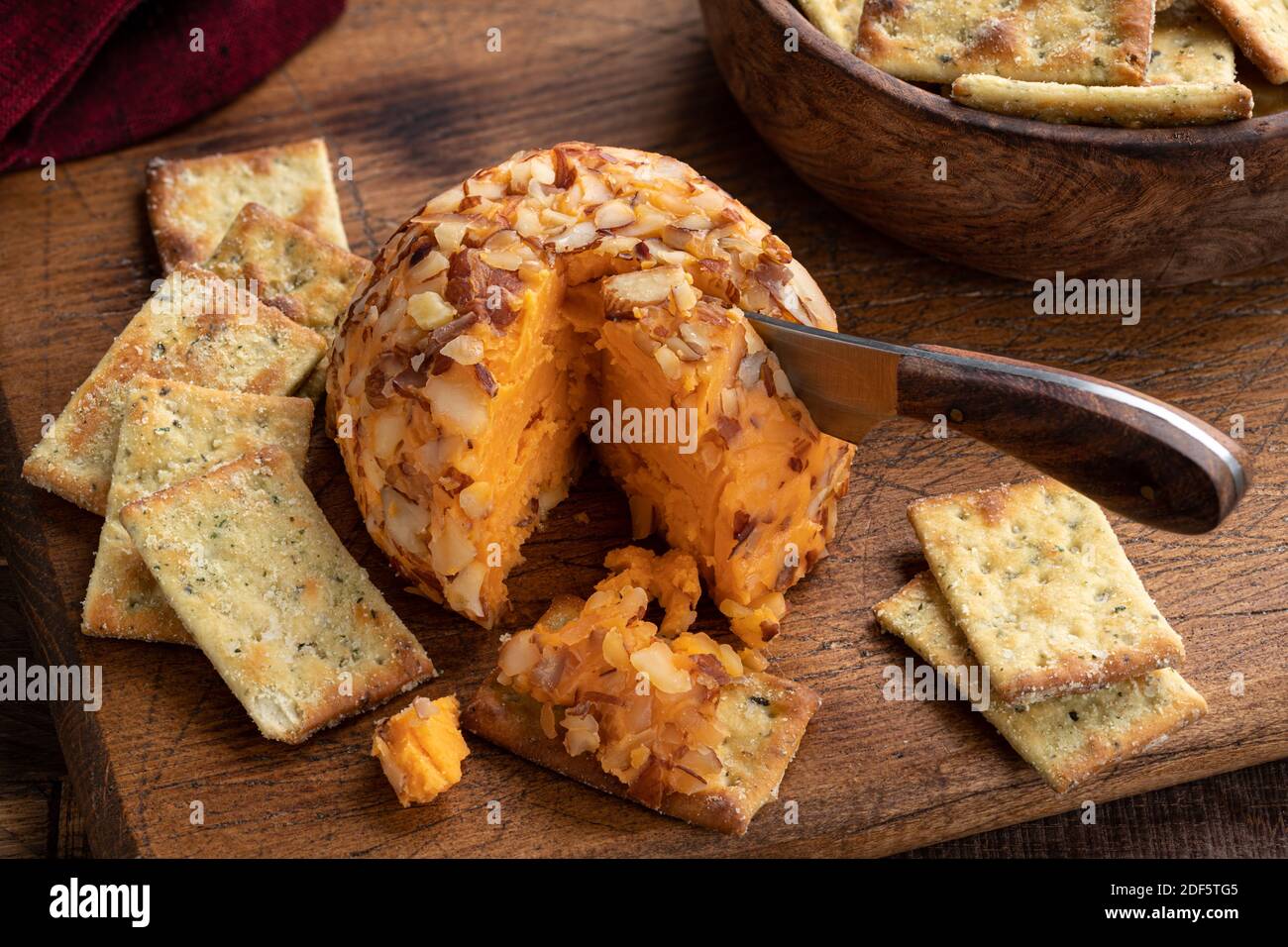 Cheddar cheese ball with nuts and crackers on a cutting board Stock Photo