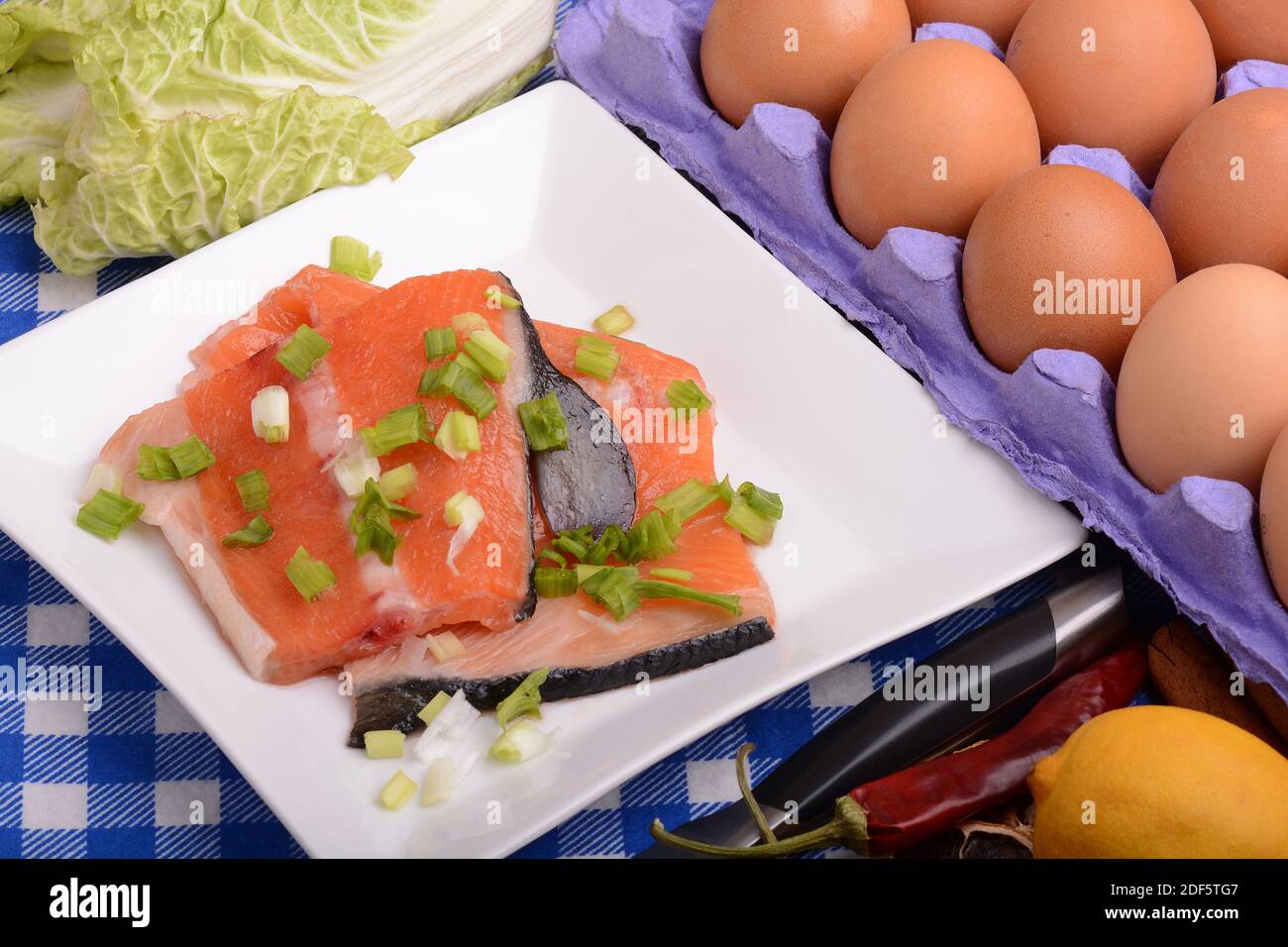 Red salmon fish, fresh eggs and cabbage with red hot chilli pepper with greens. Healthy food cooking. Stock Photo