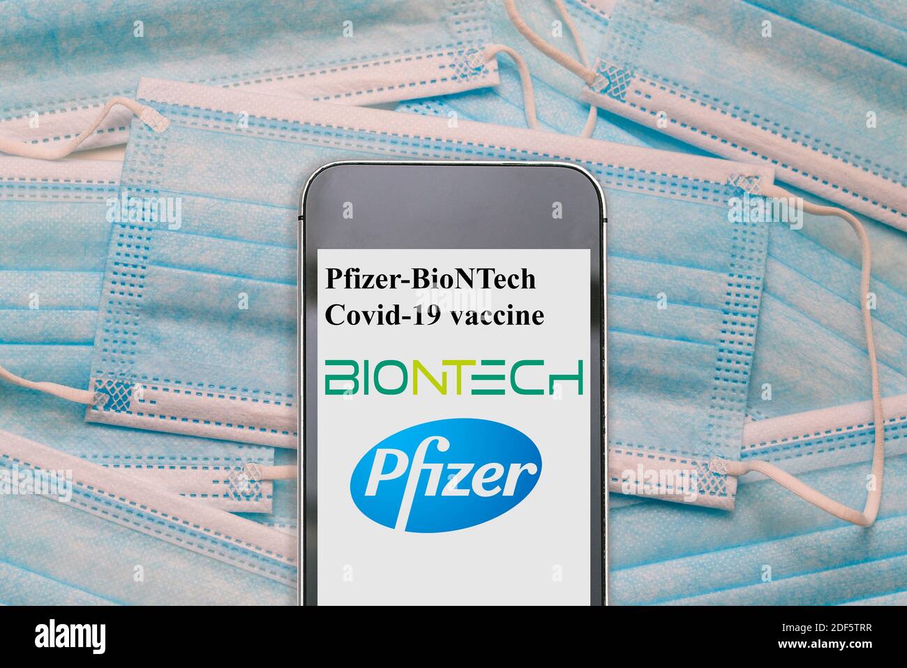 Pfizer biontech covid 19 vaccine. Reino unido vacina. UK approved pfizer vaccine. News on a smartphone. Blue disposable medical masks: NEW YORK, USA, Stock Photo