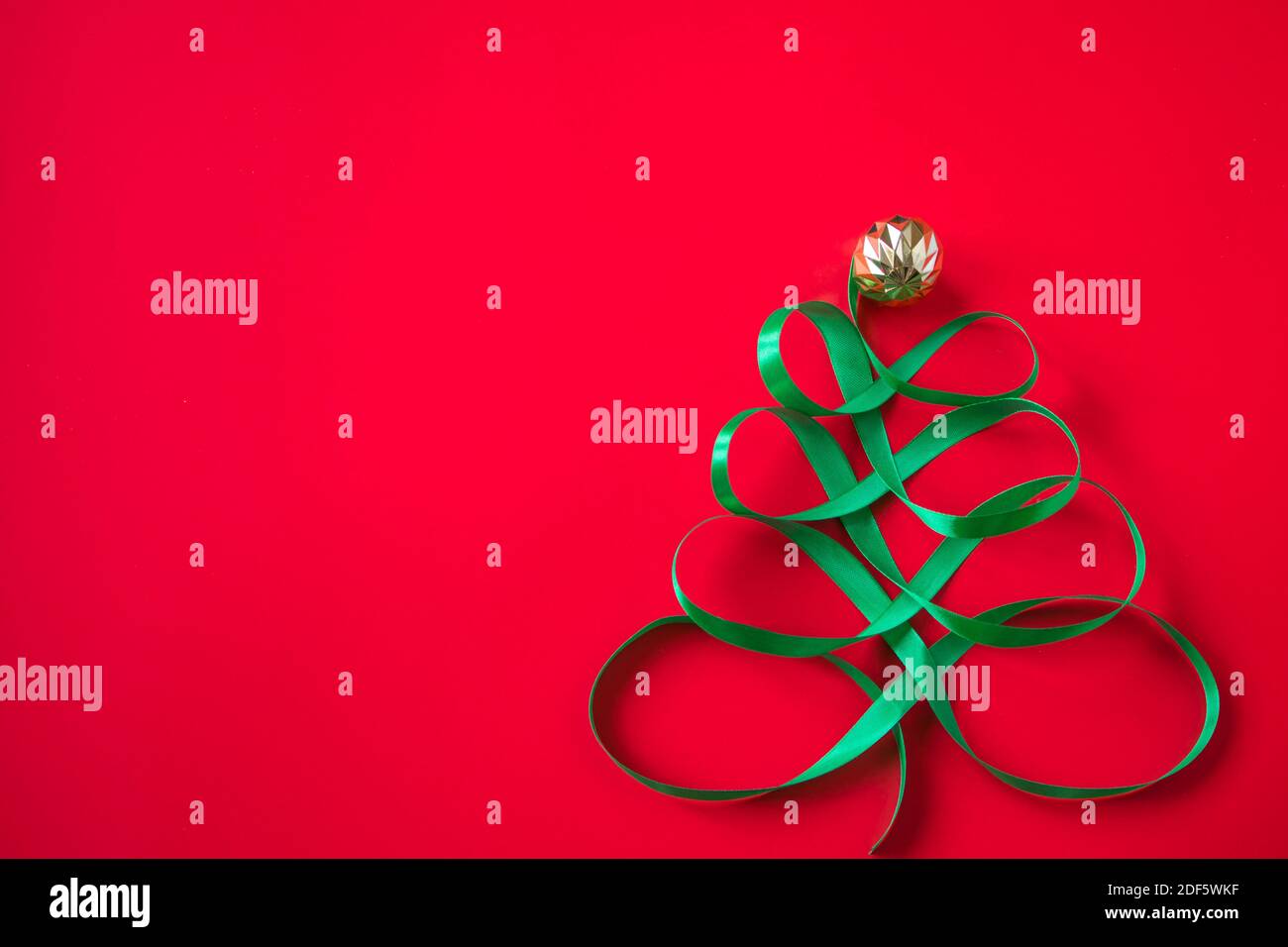 Festive tree made of satin green ribbon on red background. Creative ...