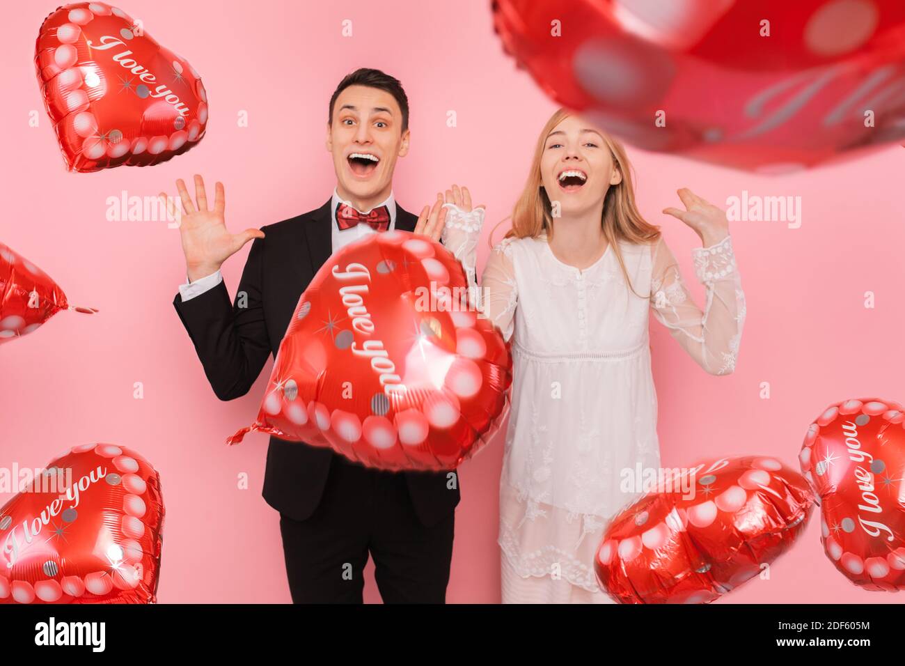 A loving couple, a man and a woman, holding heart-shaped balloons, in a ...