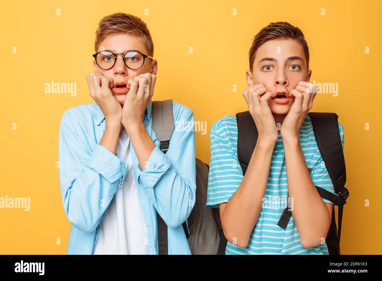 Stunned, shocked, two guys, teenagers are choking with fear, they close their mouths with both hands, they are surprised at the terrible event Stock Photo