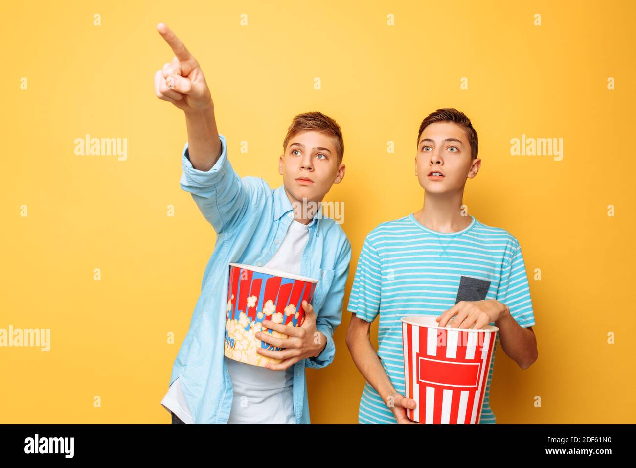 Image of two excited beautiful teenagers, guys watching an interesting movie and eating popcorn Stock Photo