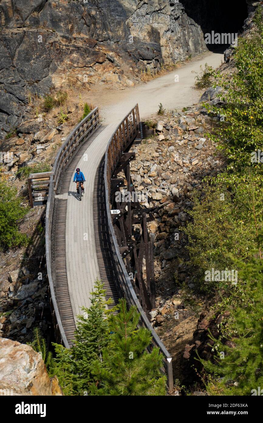 A bicyclist near a tunnel in the Myra Canyon, on the Kettle Valley Rail Trail, Okanagan, British Columbia, Canada. Stock Photo