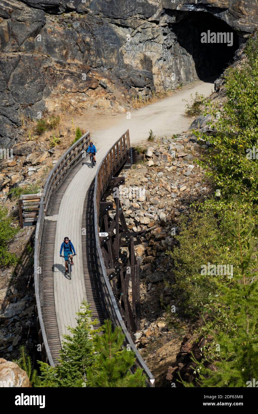 bicyclists near a tunnel in the Myra Canyon, on the Kettle Valley Rail Trail, Okanagan, British Columbia, Canada. Stock Photo