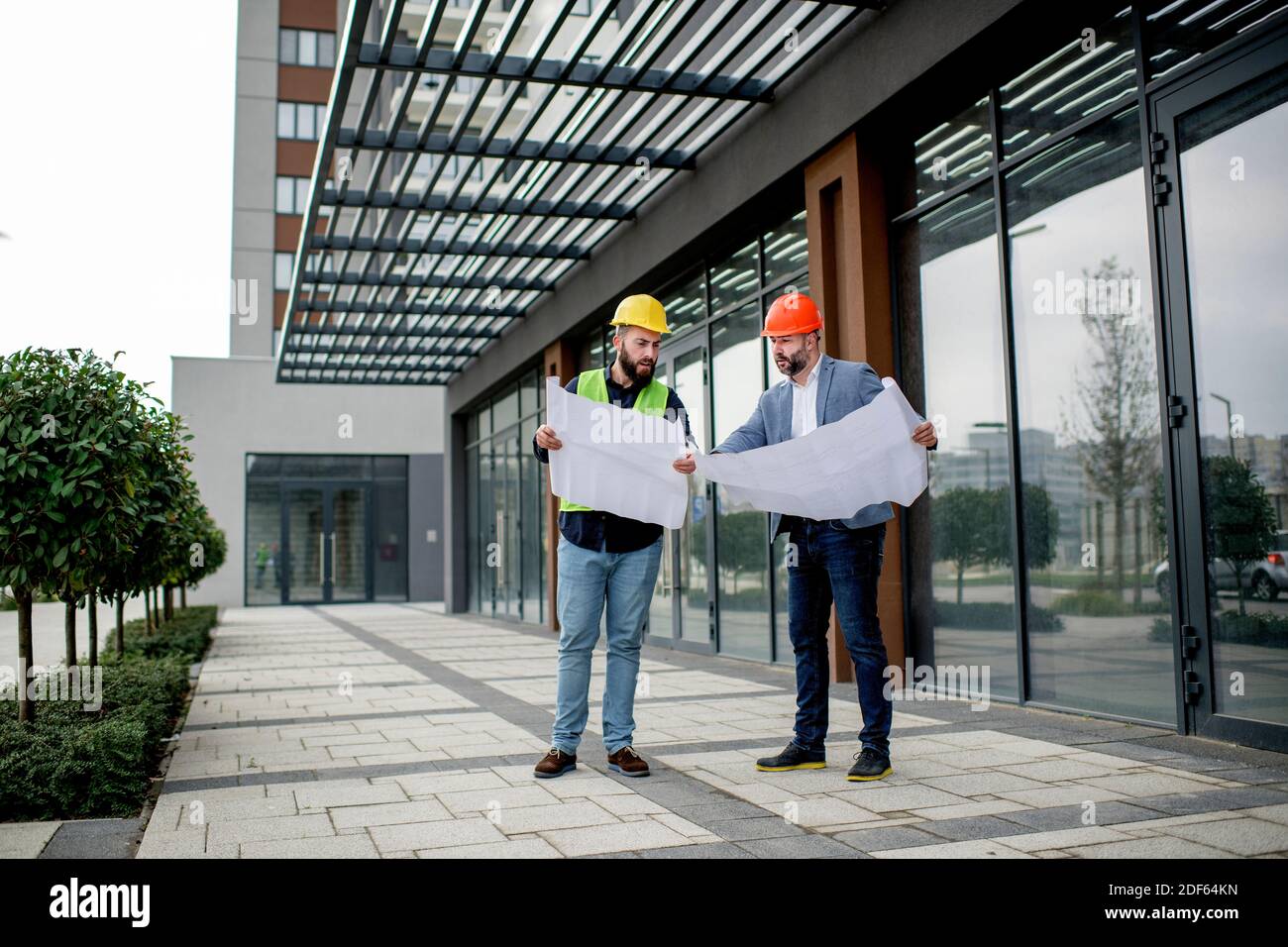 Two architects examining a blueprint and working on a building project. Stock Photo