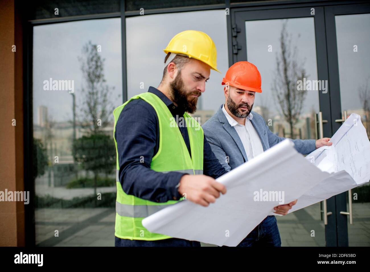 Two architects examining a blueprint and working on a building project. Stock Photo
